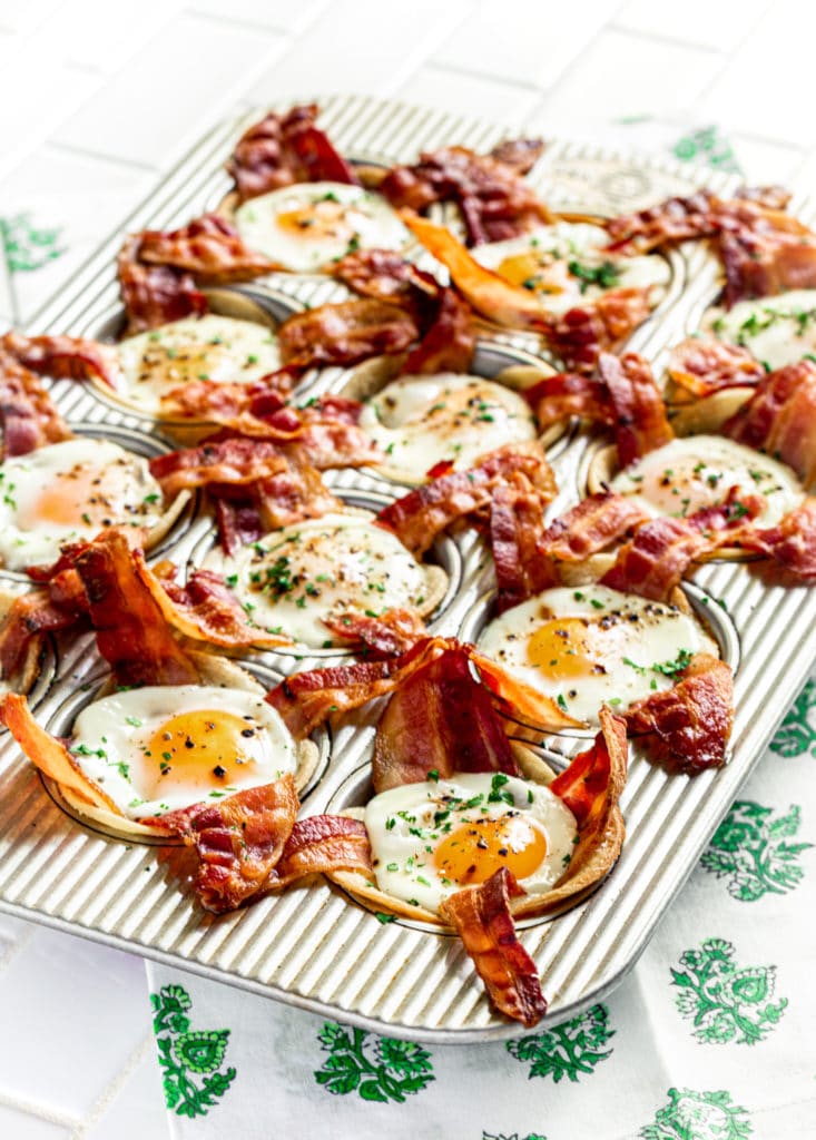 Bacon egg cups garnished with chopped parsley shown in a USA Pan 12-well muffin tin.