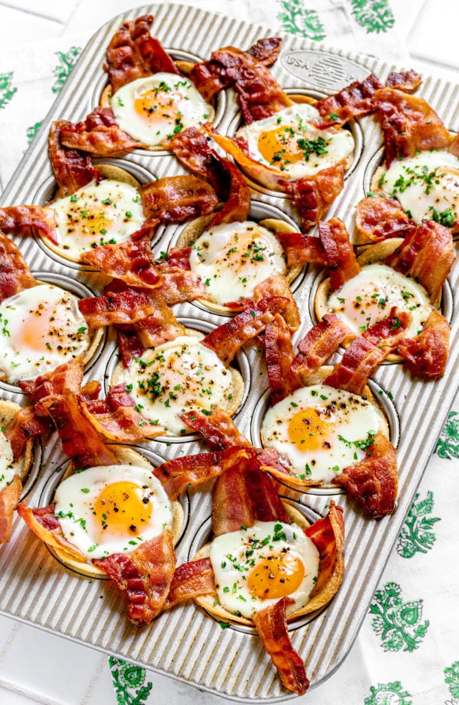 Bacon egg cups for breakfast in a muffin tin garnished with salt, pepper and parsley.
