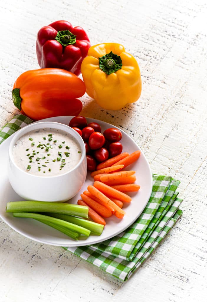 Freshly-made buttermilk dressing in a bowl with seasonal veggies and 3 colorful bell peppers.