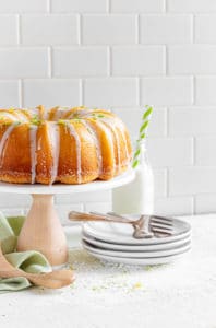 Lemon Bundt Cake on a stand with dessert plates and forks.
