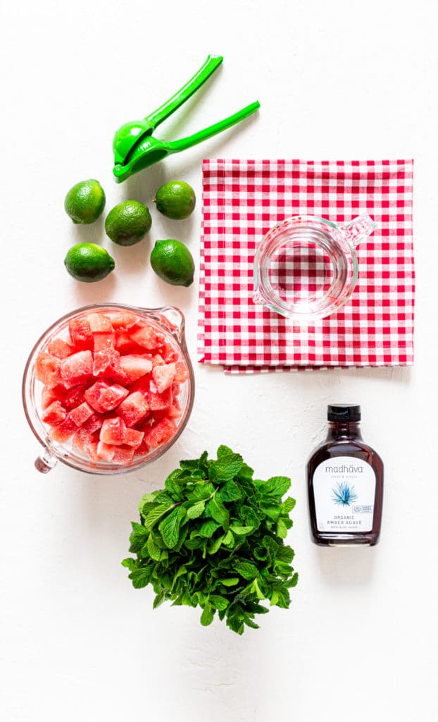 Ingredients for watermelon slushie (frozen watermelon drink) on a white tabletop.