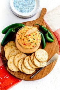 Jalapeno Pimento Cheese spread in a glass jar served on a charcuterie board with crackers.