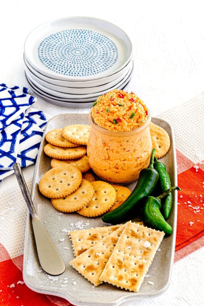 Ceramic appetizer platter with southern cheese dip, metal cheese spreader and crackers.
