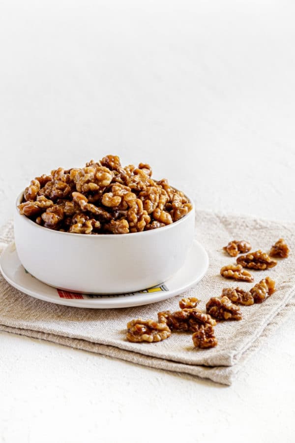A white bowl filled with candied walnuts for snacking.