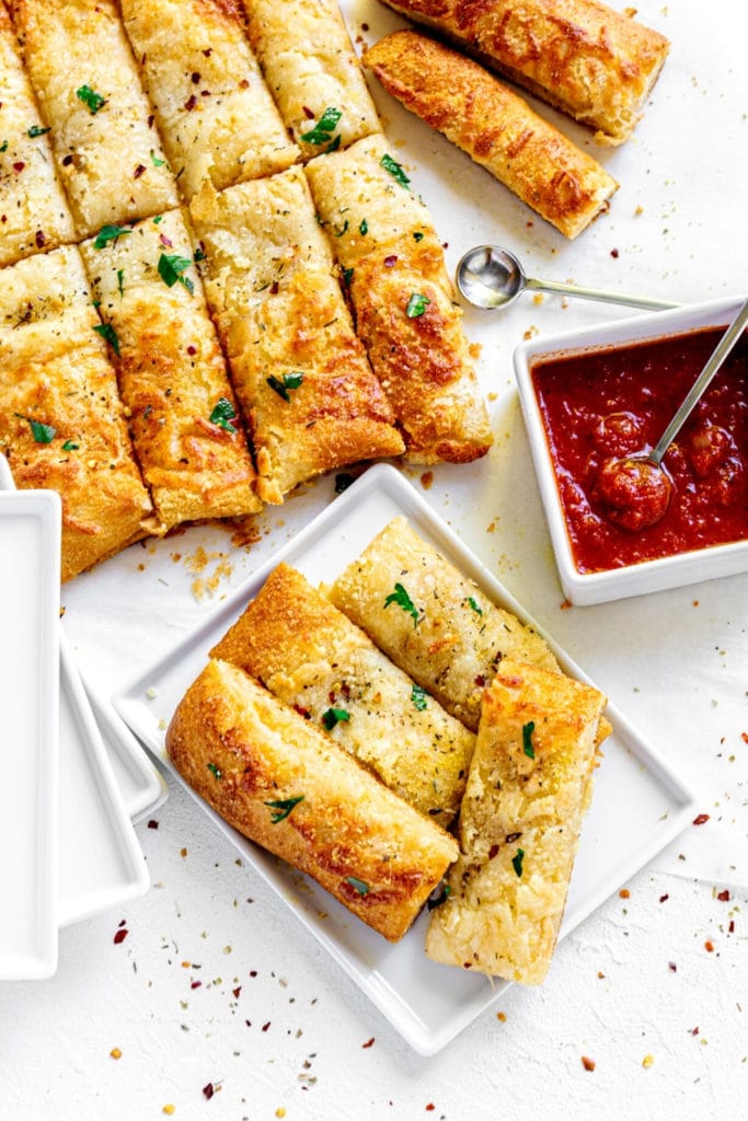 Cheesy breadsticks brushed with garlic butter and sprinkled with parsley served with marinara dipping sauce.