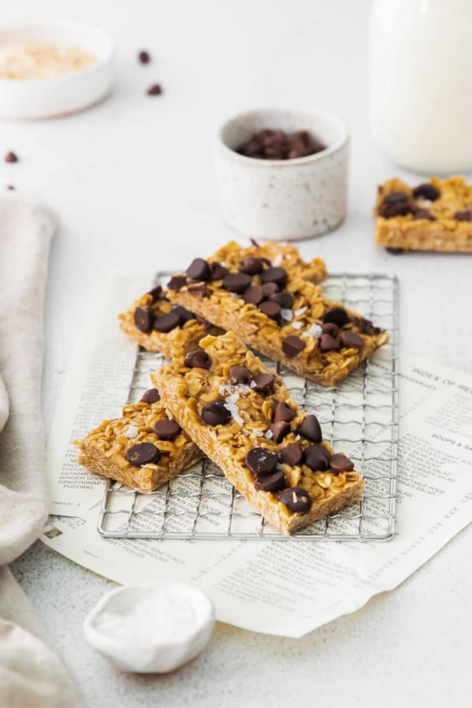 Four chewy chocolate chip granola bars garnished with flaky sea salt cooling on a wire rack.