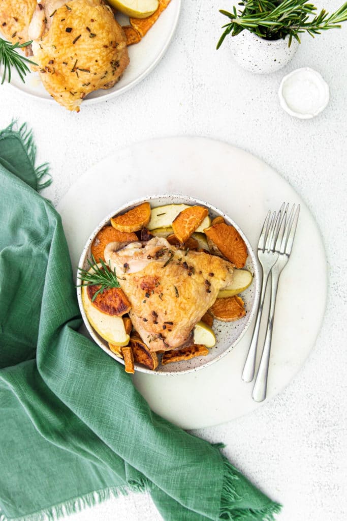 Individual serving of chicken thighs with sweet potatoes from a baked sheet pan dinner.