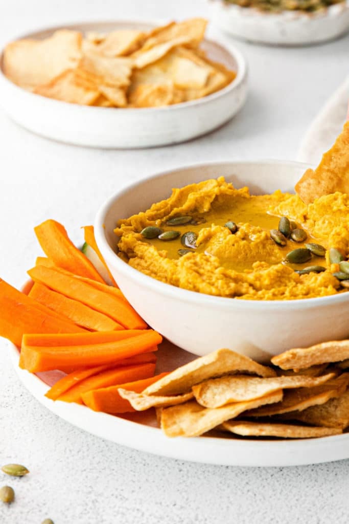 Pumpkin hummus garnished with olive oil and roasted salted pepitas.