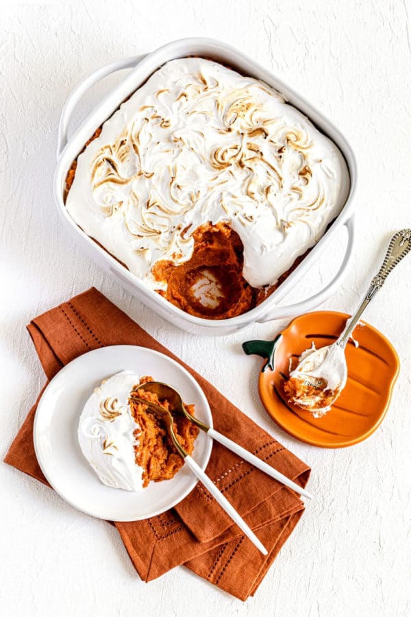 Sweet Potato Fluff Casserole in a white baking dish plus a serving with spoon and fork.