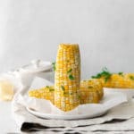Air fryer corn on the cob garnished with butter, salt and fresh parsley.