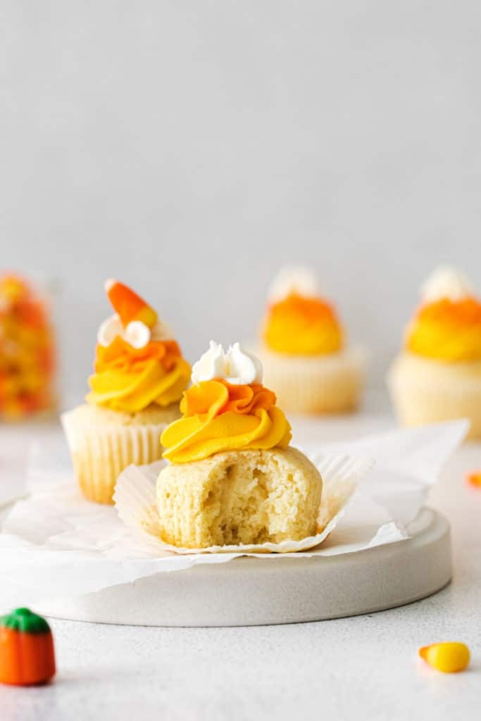 A frosted candy corn cupcake with a bite taken out.