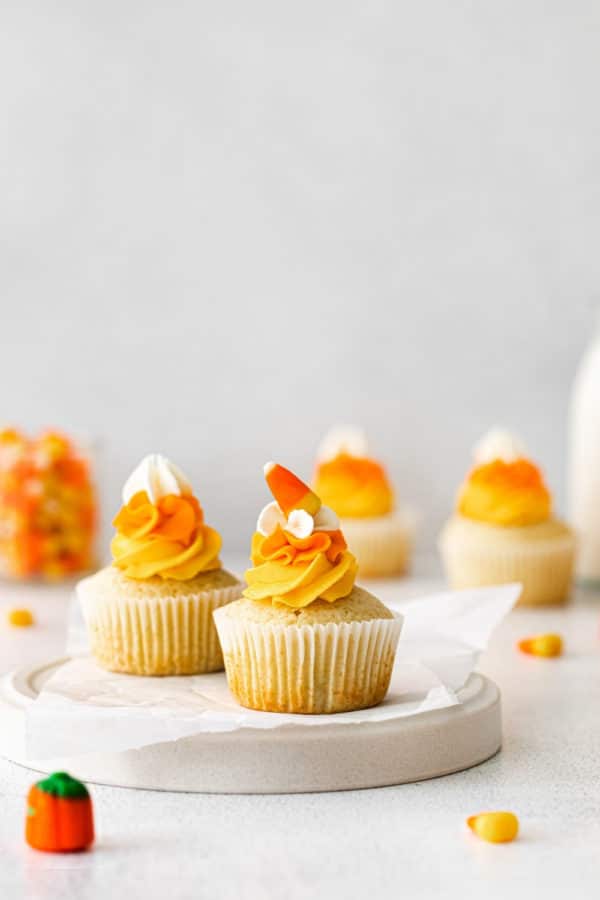 Candy corn cupcakes with swirls of multi-color frosting on a Halloween dessert table.