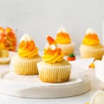 Vanilla Halloween cupcakes with swirled white/orange/yellow frosting garnished with candy corn.