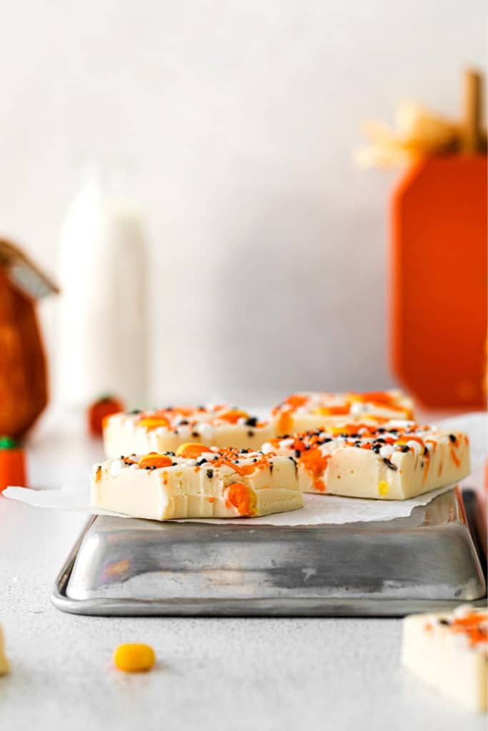 Halloween dessert squares with candy corn and Halloween sprinkles. One square has a bite taken out.