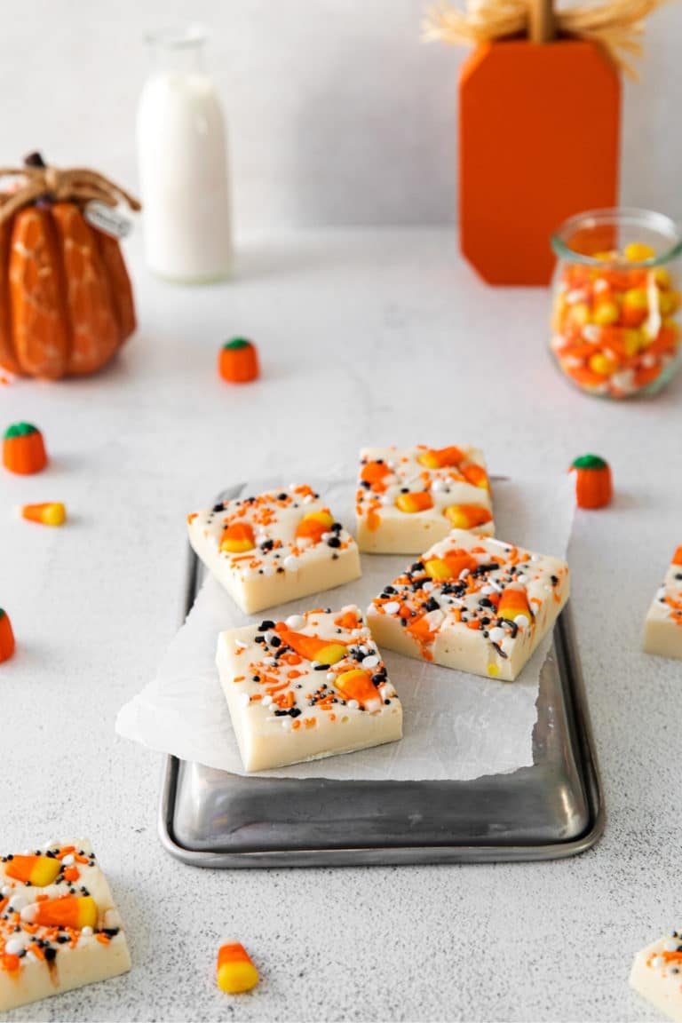 Squares of candy corn fudge garnished with orange/white/black candy sprinkles and candy corn.