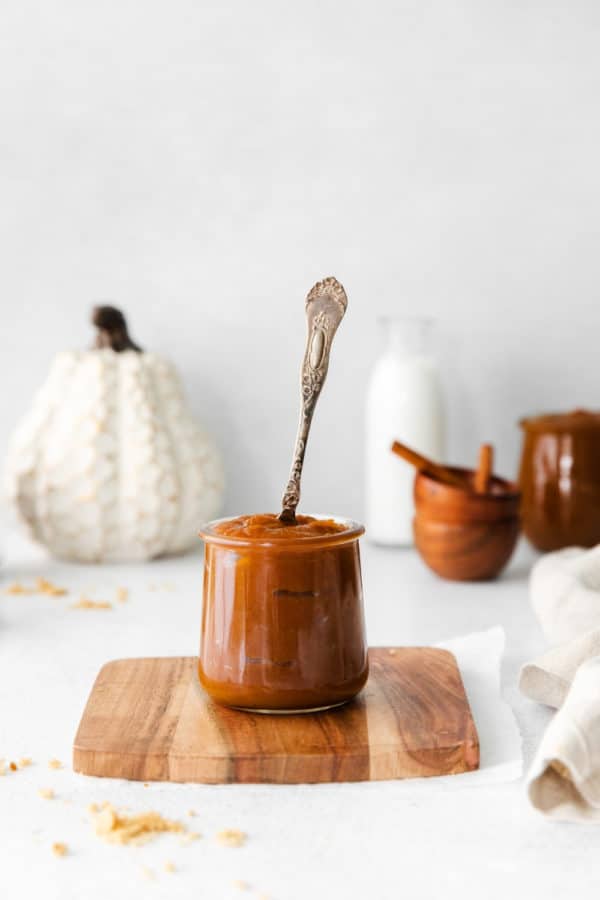A small jar of freshly-made pumpkin butter with a silver spoon.