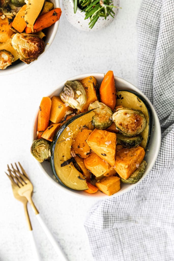 Roasted Autumn Veggies in a white bowl with a napkin and fork.