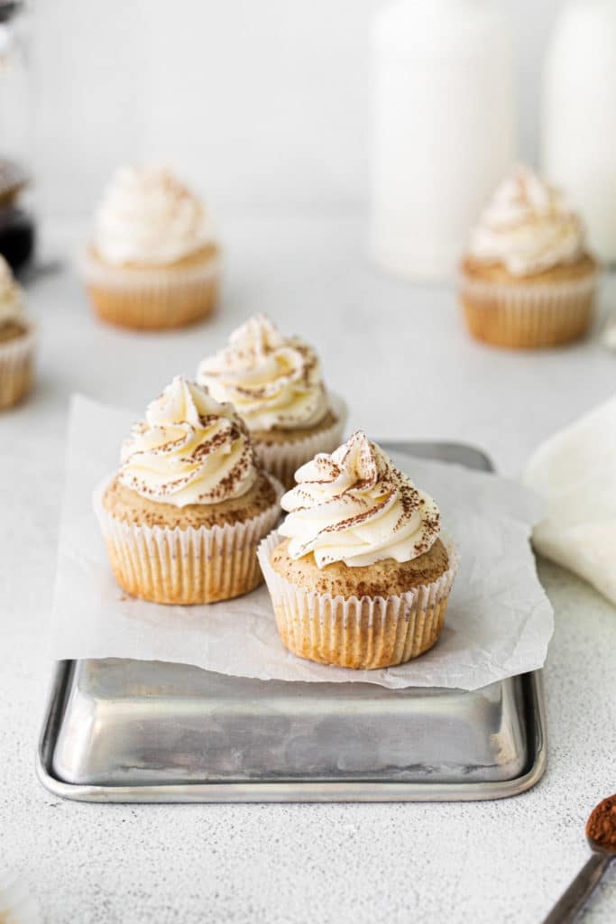 Three tiramisu cupcakes iced with swirls of mascarpone frosting and dusted with finely-grated chocolate.
