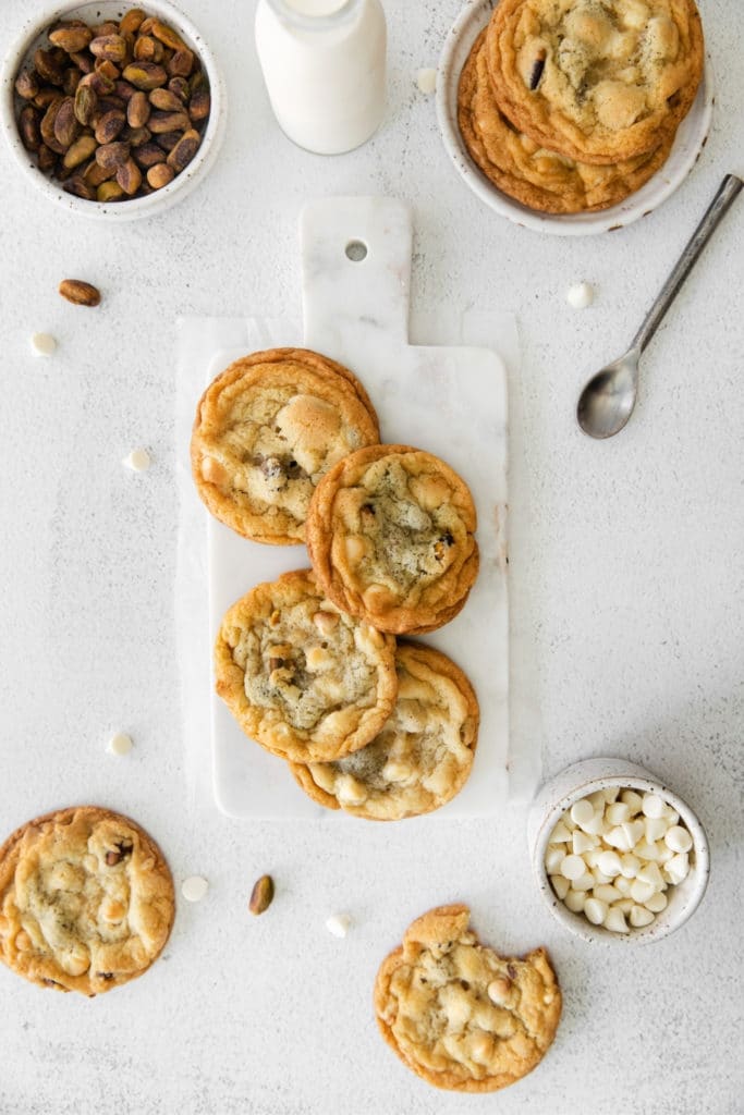 Fresh, homemade, white chocolate chip cookies served on a marble board on tabletop.