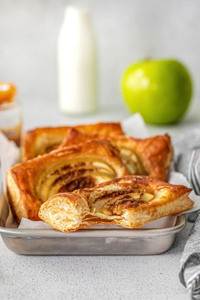 Apple Puff Pastry Squares arranged on a small metal tray with a bottle of milk nearby.