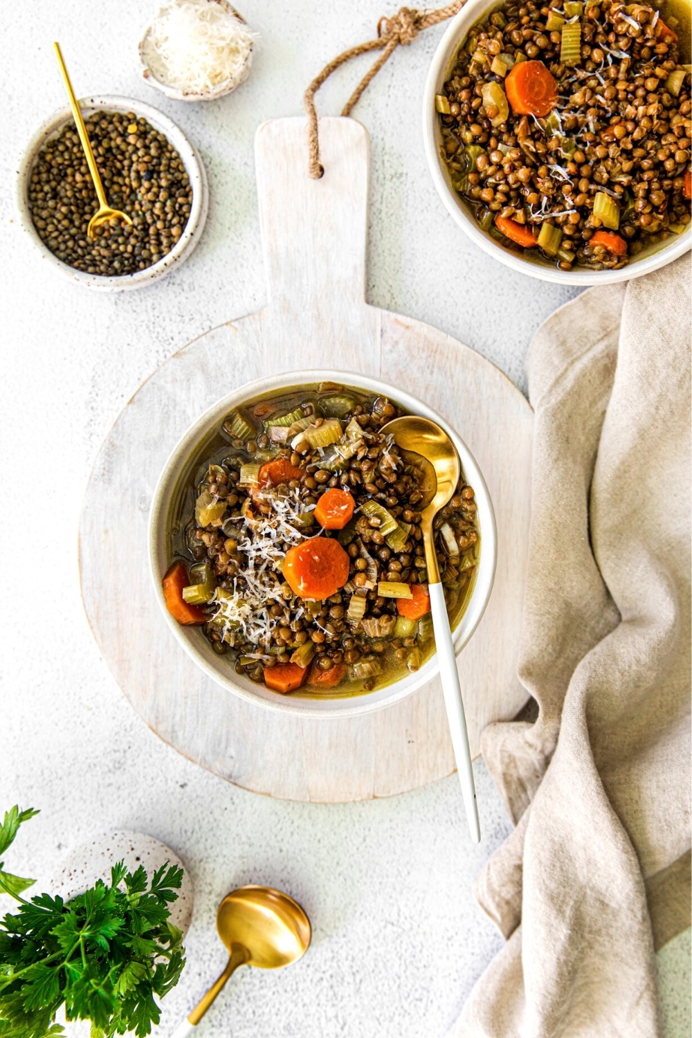 Green lentil soup on a serving table with Parmesan cheese and Italian parsley.