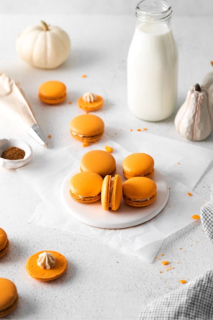 Decorating orange-colored Pumpkin Spice Macarons with buttercream frosting.