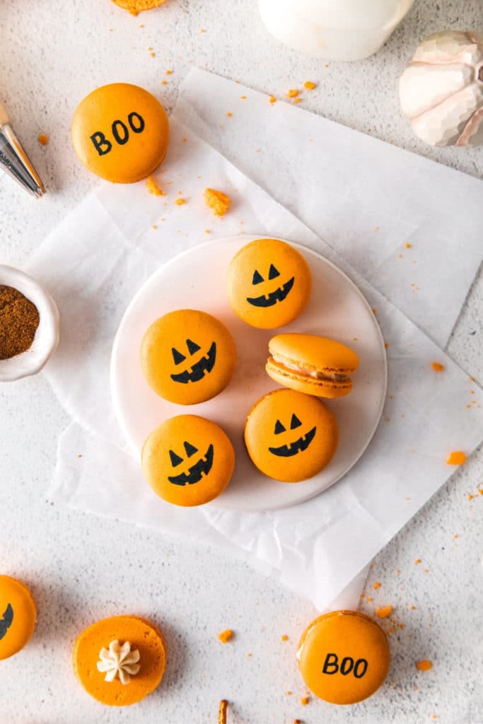 French Halloween Pumpkin Macarons with spooky Jack 'o Lantern faces.