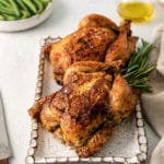 Roasted cornish hen on a serving platter with sprigs of fresh rosemary.