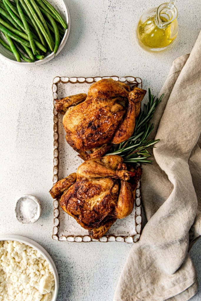 Holiday table featuring roasted Cornish hen with rosemary garnish and French green beans.