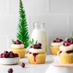 Cranberry cupcakes garnished with buttercream frosting, sugared cranberries plus a sprig of rosemary for a pop of color.