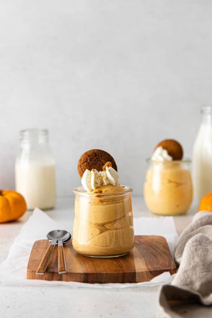 Pumpkin cheesecake mousse parfait topped with whipped cream and a gingersnap cookie.