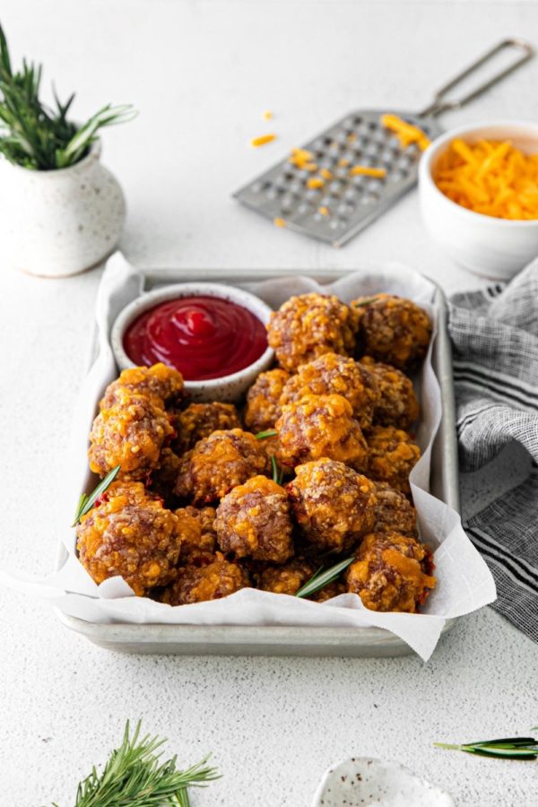 Bisquick sausage cheese balls presented in a serving tray with a small bowl of ketchup.