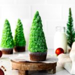 Christmas tree cupcakes on a holiday dessert table with milk.