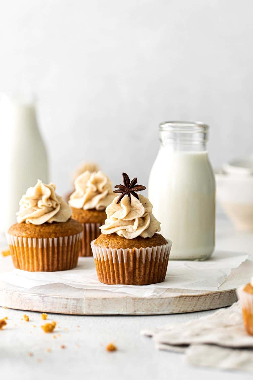 Ginger Spice Cupcakes on a white wooden board next to glass bottles of milk.