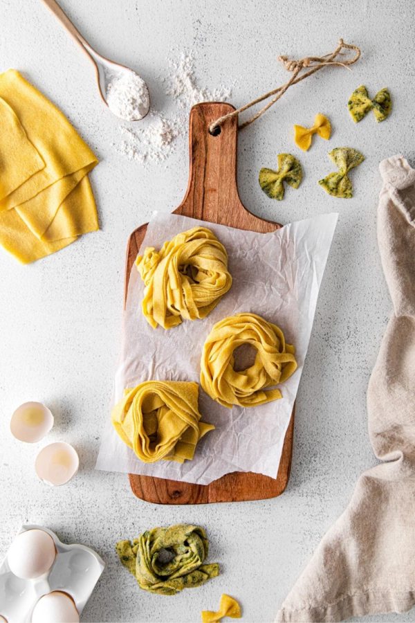 Three pasta nests assembled with authentic homemade pasta dough laid out on a wooden board.