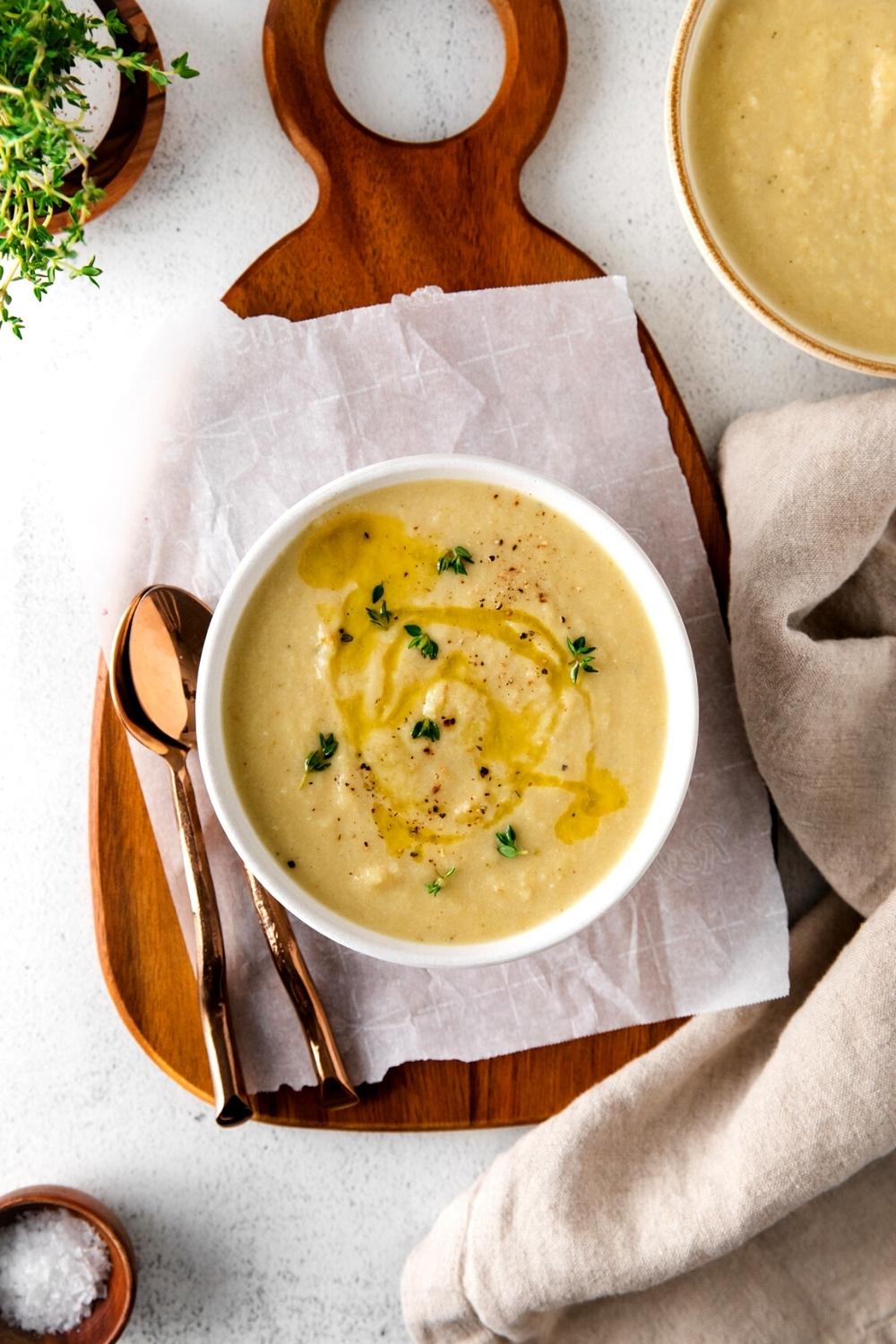 Bowl of creamy roasted cauliflower leek soup garnished with olive oil and fresh thyme.