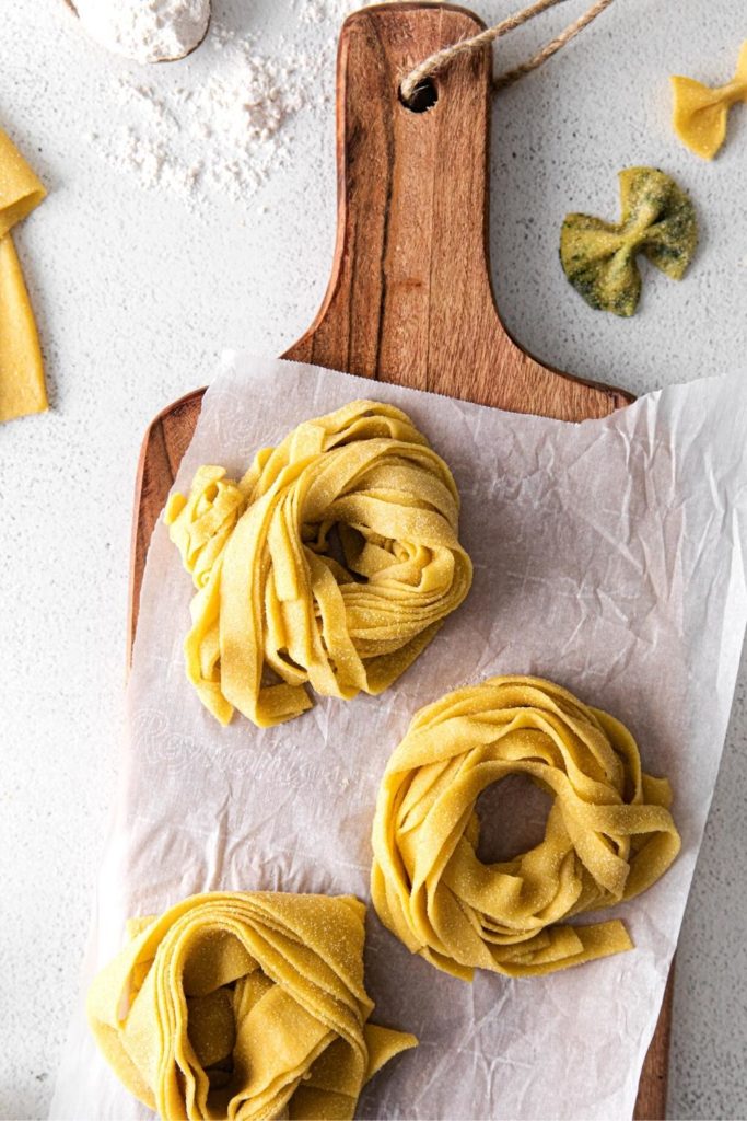 Fresh homemade pasta cut into strips, drying on a wooden board in pasta nests.