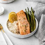 Lemon garlic butter sheet pan salmon served in individual bowls with asparagus and rice.