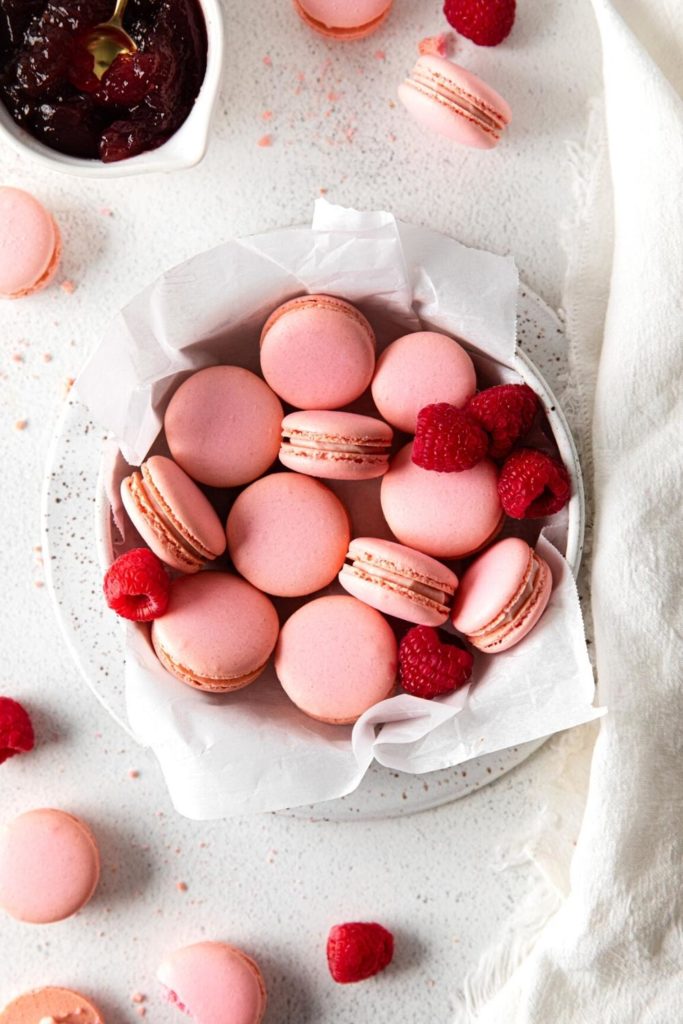 A cookie dish filled with raspberry macarons.