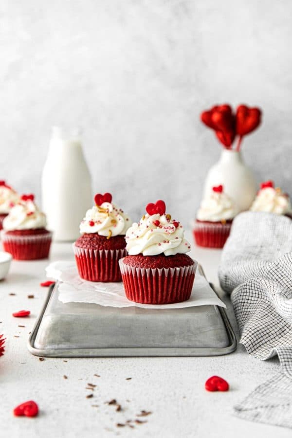 Red velvet cupcakes with cream cheese frosting decorated with Valentine's Day candy sprinkles.