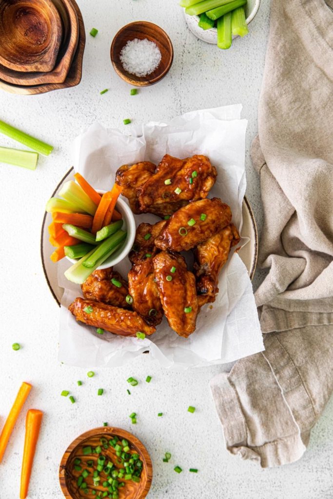 Tasty baked BBQ Chicken Wings garnished with a sprinkling of sliced green onions.