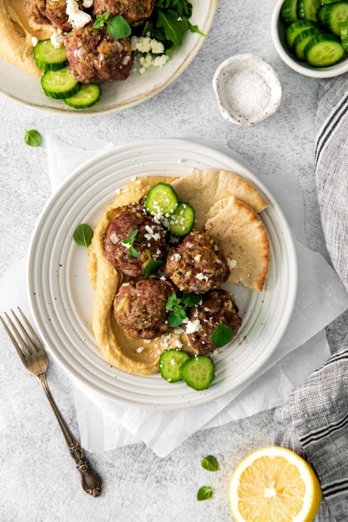 Greek lamb meatballs sprinkled with feta cheese and fresh oregano leaves. Served with hummus and flatbread.