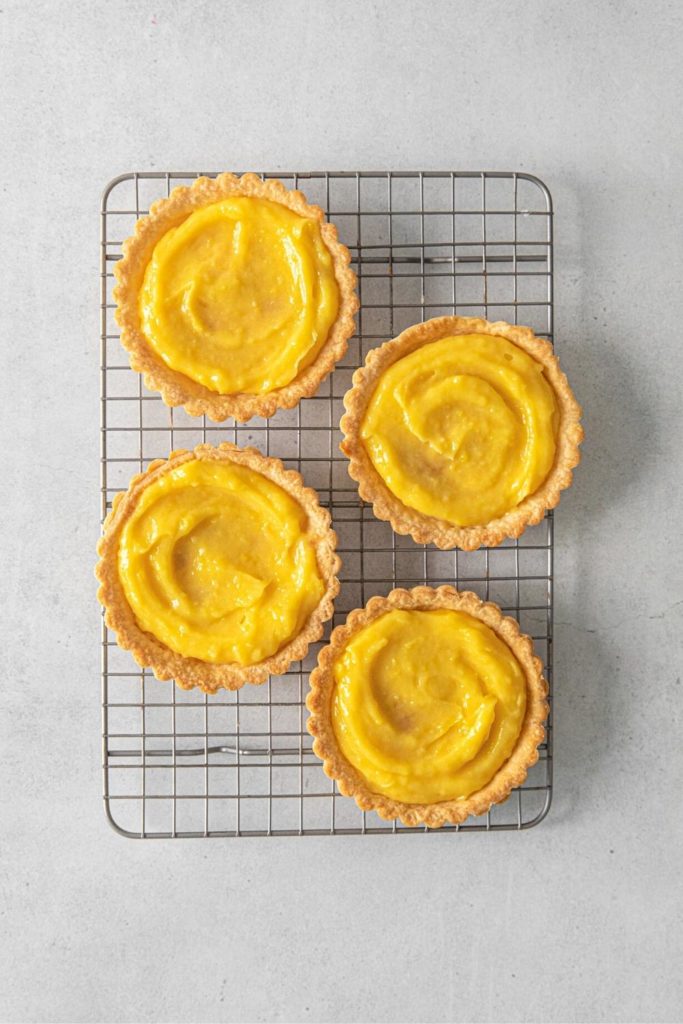 Lemon curd spooned into the middle of 4 mini tart shells.