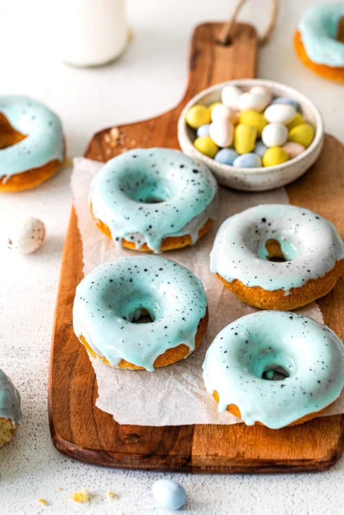 Freshly-baked Robin's Egg Easter Donuts on a wooden board with mini Cadbury eggs.