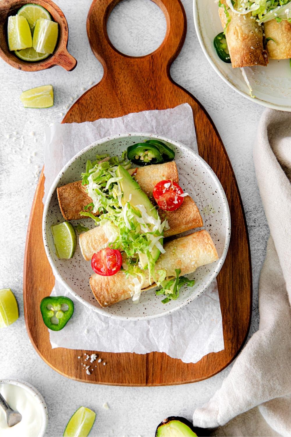 Air fryer chicken taquitos served in a bowl and garnished with fresh produce.