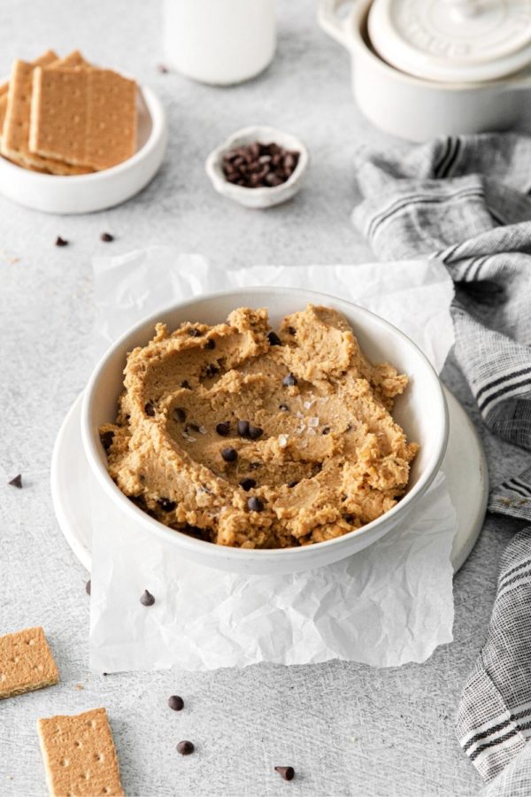 Bowl of chickpea cookie dough hummus with mini chocolate chips served with graham crackers.