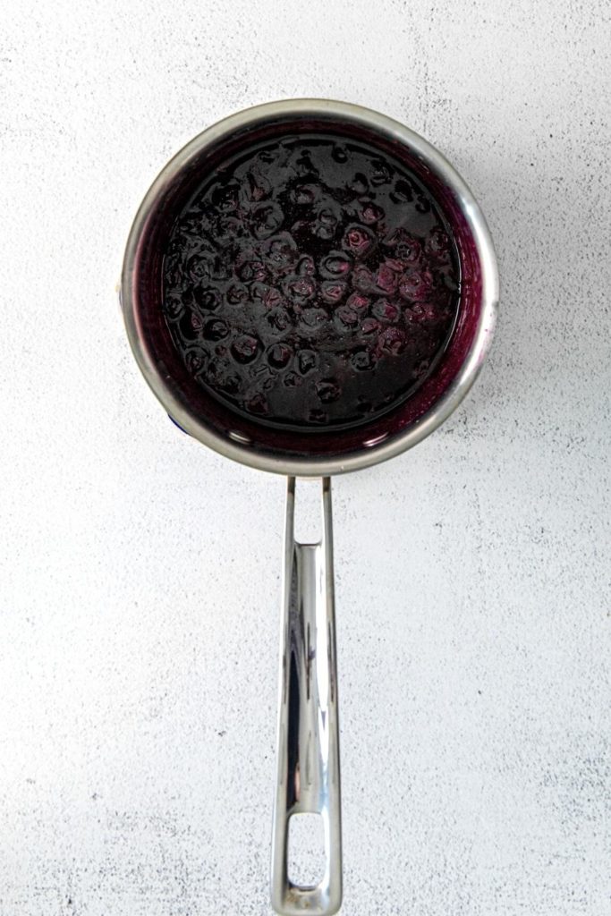 Blueberry compote being prepared in a small pan.