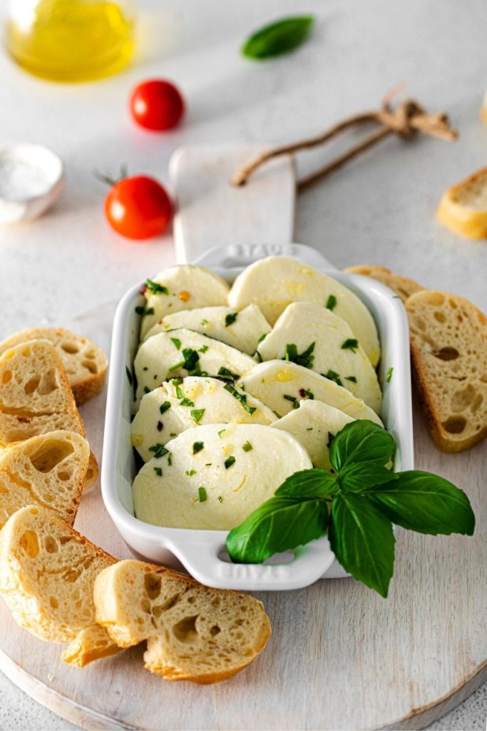 Marinated cheese garnished with fresh basil leaves.
