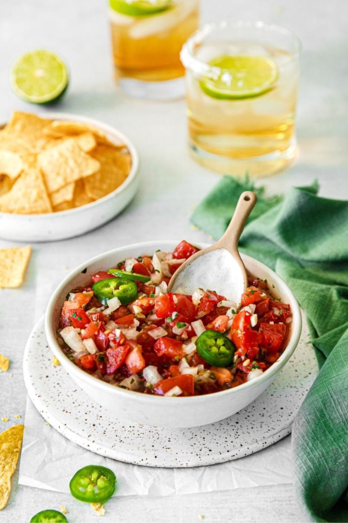 Pico de Gallo in a bowl on a Cinco de Mayo table with chips and drinks.