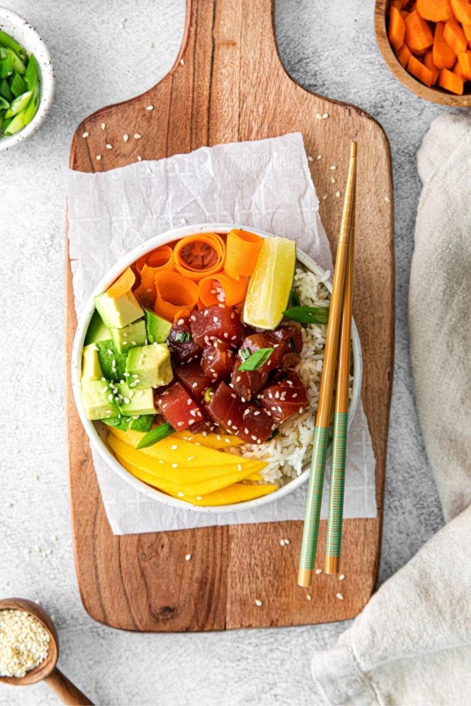 Spicy tuna poke bowl garnished with sesame seeds and a slice of lime.